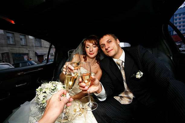A bride and groom celebrate in a limo, holding champagne flutes, with a sign reading "Limo for Your Anniversary" visible.