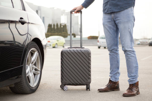 A black car's headlights are on in a dark environment, signaling its role in airport transportation.