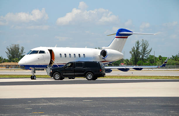 A black car shines its headlights in the dark, suggesting it is ready for airport transportation.